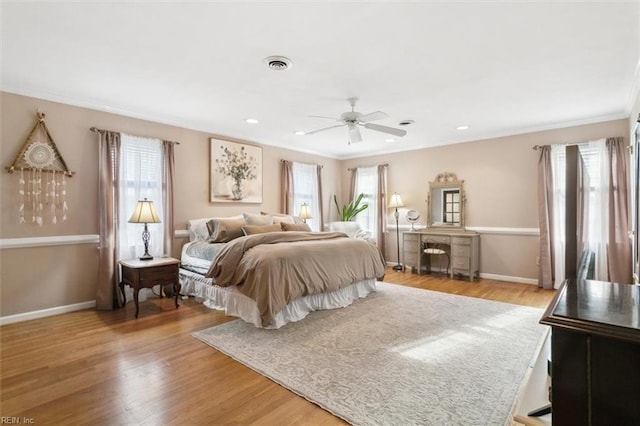 bedroom featuring multiple windows, wood finished floors, visible vents, and baseboards