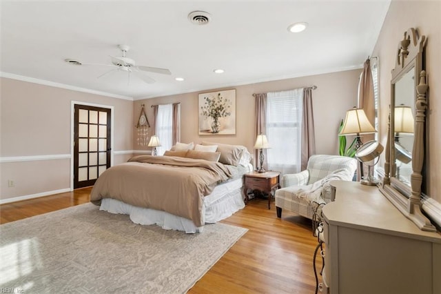 bedroom with light wood-type flooring, visible vents, crown molding, and multiple windows