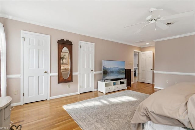 bedroom featuring wood finished floors, a ceiling fan, visible vents, baseboards, and crown molding