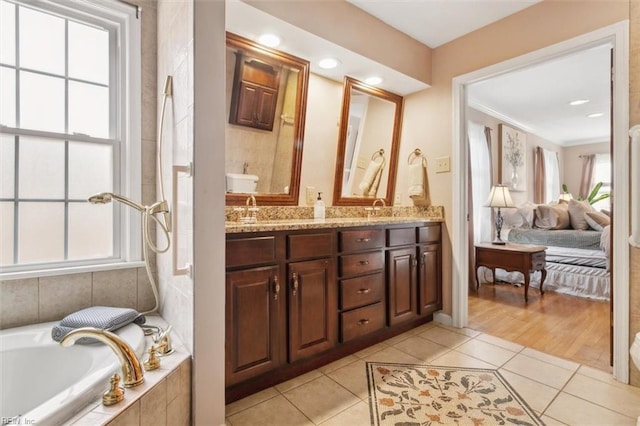 ensuite bathroom with a healthy amount of sunlight, a sink, and tile patterned floors