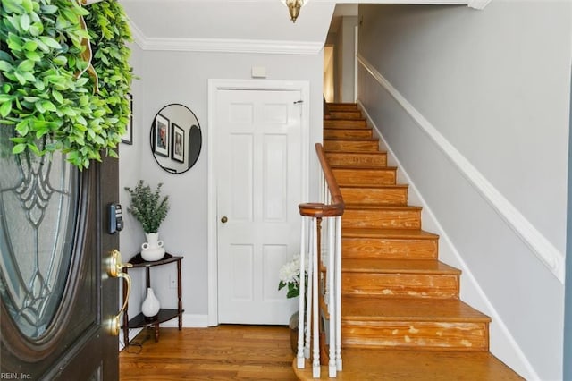 foyer with stairs, crown molding, baseboards, and wood finished floors