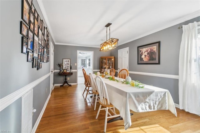 dining room featuring baseboards, wood finished floors, and crown molding