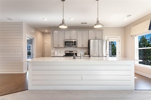 kitchen featuring visible vents, stainless steel appliances, tasteful backsplash, and a kitchen island with sink