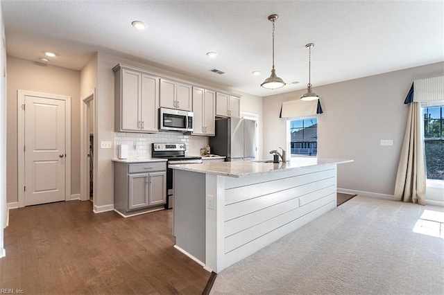 kitchen featuring stainless steel appliances, gray cabinets, visible vents, decorative backsplash, and an island with sink