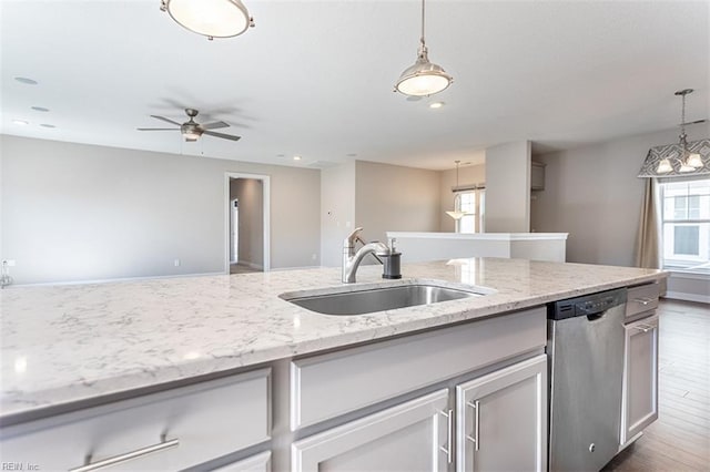 kitchen featuring light stone counters, a sink, stainless steel dishwasher, dark wood finished floors, and pendant lighting