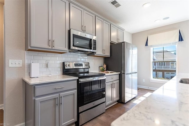 kitchen featuring tasteful backsplash, visible vents, dark wood finished floors, stainless steel appliances, and gray cabinetry