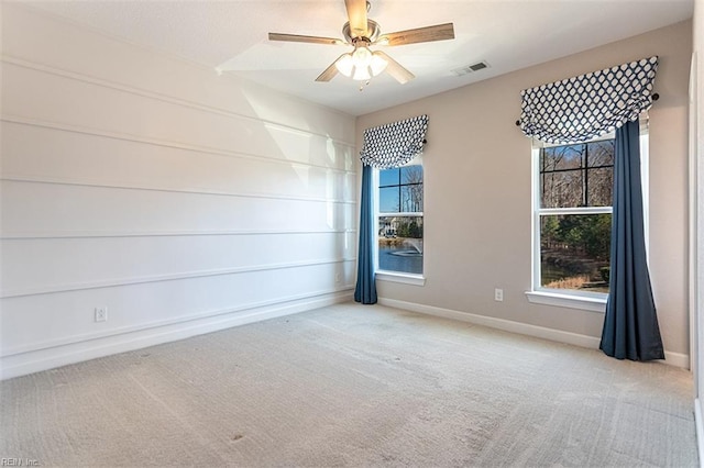 spare room with baseboards, carpet, visible vents, and a ceiling fan