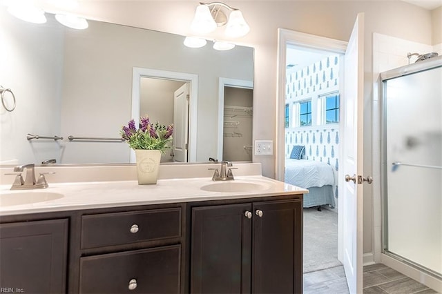 full bath featuring double vanity, a sink, connected bathroom, and a shower stall