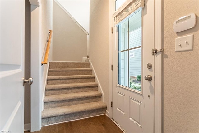 interior space with stairs, a textured wall, and dark wood-style flooring