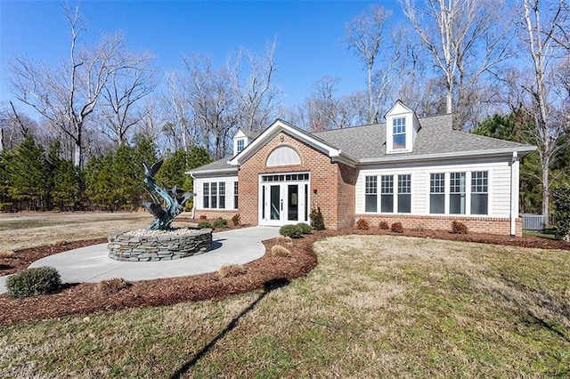 view of front of home featuring french doors, brick siding, roof with shingles, a front yard, and cooling unit