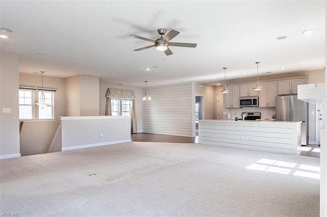 unfurnished living room featuring a wealth of natural light, light carpet, baseboards, and recessed lighting