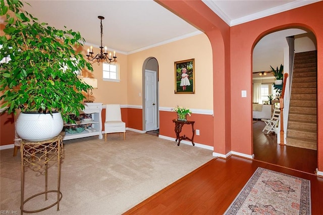 sitting room with baseboards, stairs, arched walkways, and crown molding