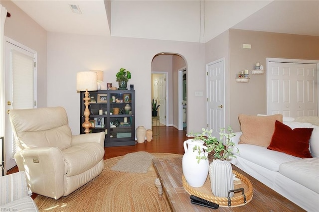 living room with visible vents, arched walkways, and wood finished floors