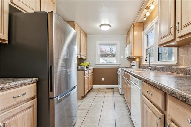 kitchen with light brown cabinets, white appliances, light tile patterned flooring, and a sink