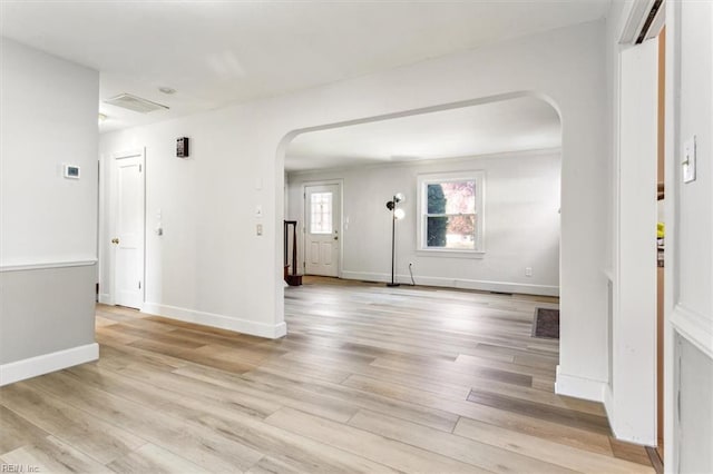 entrance foyer with light wood-style flooring, arched walkways, and baseboards