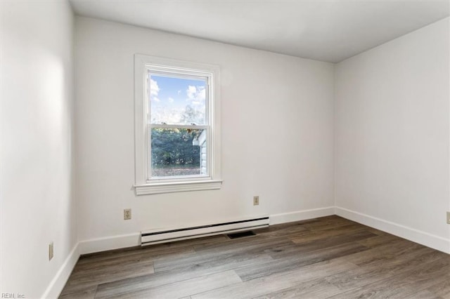 empty room with baseboard heating, wood finished floors, and baseboards