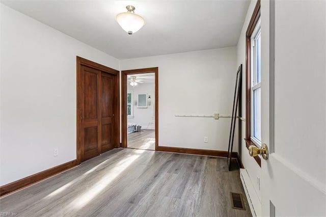 unfurnished bedroom featuring light wood finished floors, connected bathroom, visible vents, and baseboards