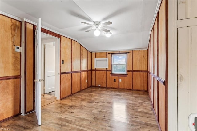 spare room with ceiling fan, vaulted ceiling, wood walls, and wood finished floors