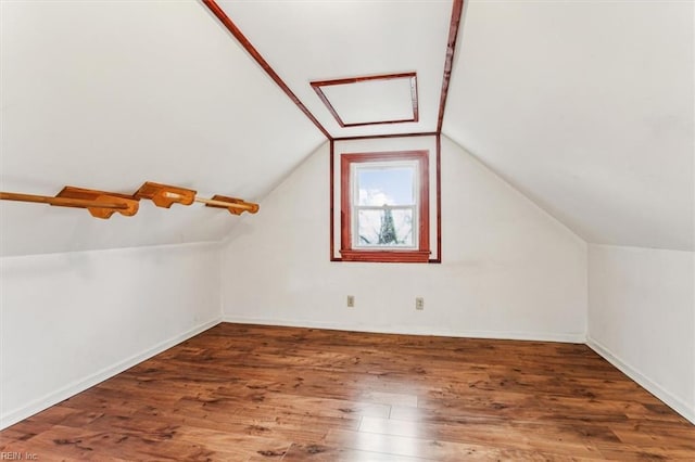 additional living space with vaulted ceiling, wood finished floors, and baseboards