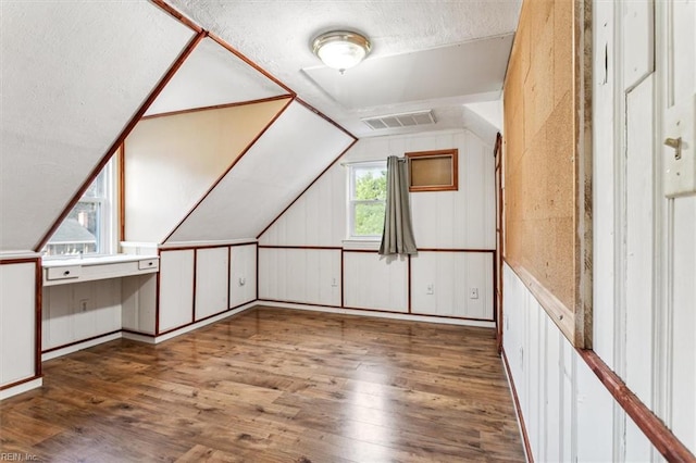 additional living space featuring lofted ceiling, visible vents, and wood finished floors