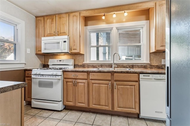 kitchen with white appliances, light tile patterned floors, decorative backsplash, and a sink