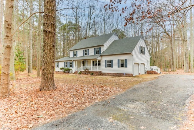 view of front facade with a porch, roof with shingles, driveway, and a garage