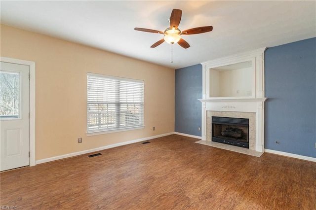 unfurnished living room with a large fireplace, a ceiling fan, baseboards, and wood finished floors