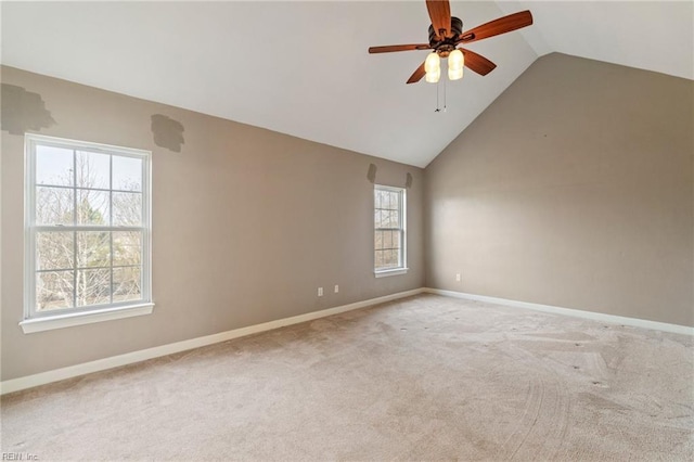 spare room with light carpet, high vaulted ceiling, a ceiling fan, and baseboards