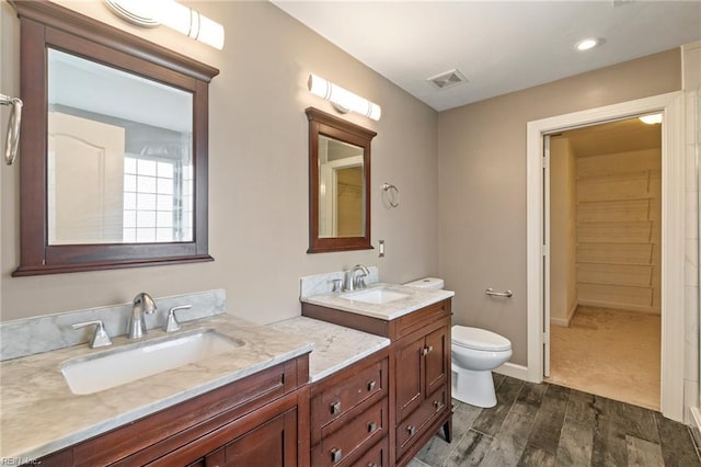 full bath with visible vents, a sink, toilet, and double vanity