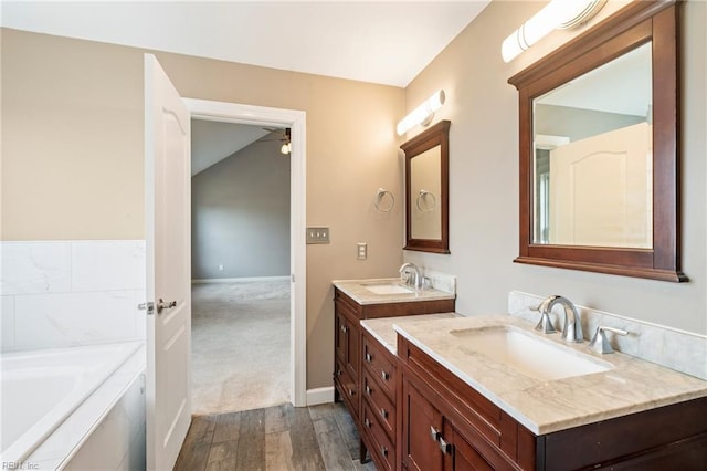 full bath featuring baseboards, wood finished floors, a bath, and vanity