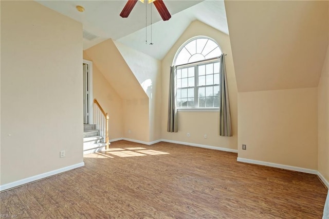 additional living space featuring baseboards, stairway, vaulted ceiling, and wood finished floors