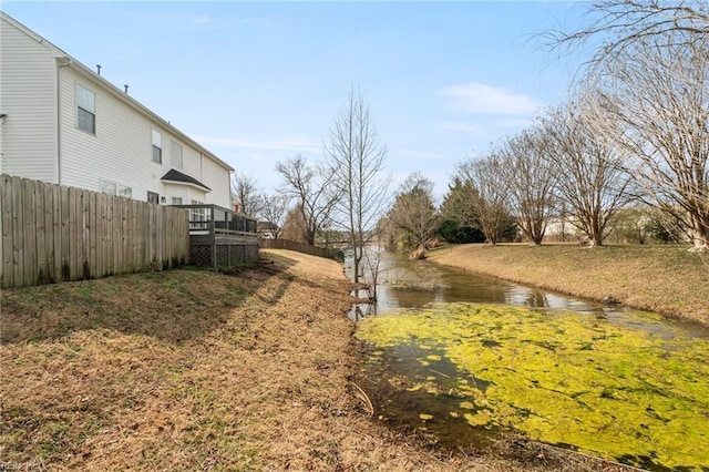 view of yard featuring a deck with water view and fence