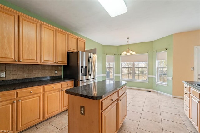 kitchen with a center island, stainless steel fridge, decorative backsplash, and light tile patterned flooring