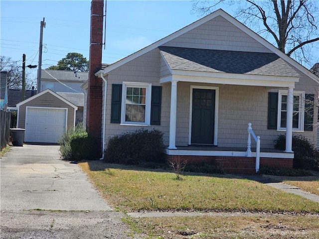 view of front of home featuring concrete driveway, a detached garage, an outbuilding, roof with shingles, and covered porch