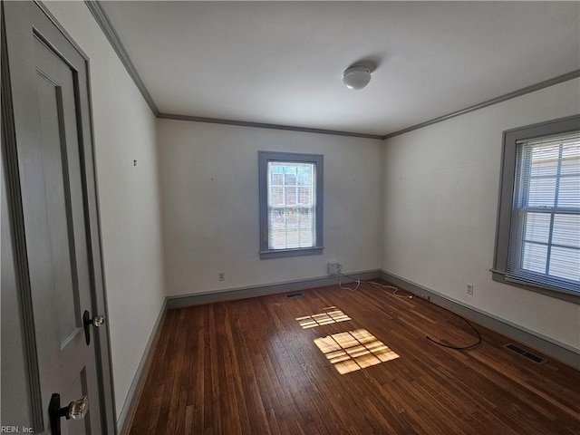 unfurnished room featuring ornamental molding, plenty of natural light, wood finished floors, and visible vents