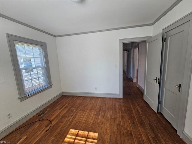 unfurnished room featuring dark wood finished floors, visible vents, crown molding, and baseboards