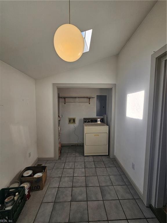 unfurnished dining area with washer / dryer, vaulted ceiling with skylight, light tile patterned flooring, and baseboards