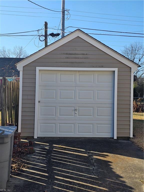 detached garage featuring driveway and fence