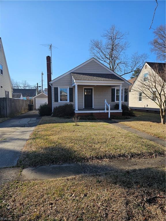 bungalow featuring a chimney, an outbuilding, fence, a porch, and a front yard