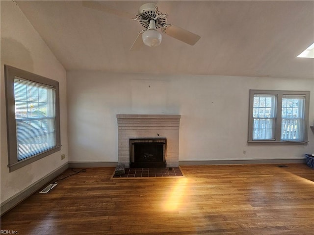 unfurnished living room with vaulted ceiling, a fireplace, wood finished floors, and a healthy amount of sunlight