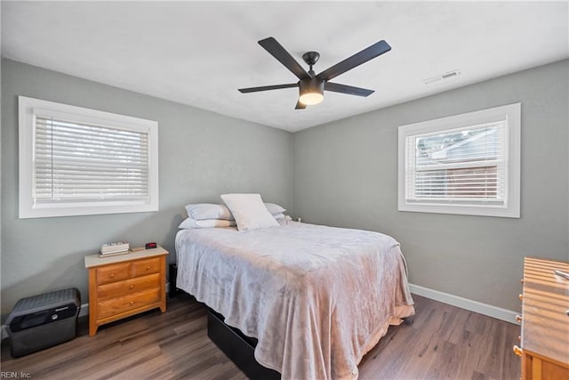 bedroom with dark wood-style floors, visible vents, ceiling fan, and baseboards