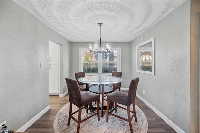 dining space with a chandelier, dark wood-style flooring, a textured wall, and baseboards