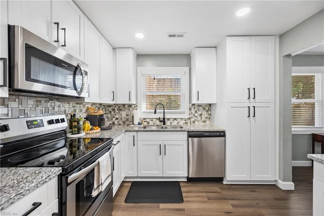 kitchen featuring stainless steel appliances, dark wood-style flooring, a sink, and visible vents