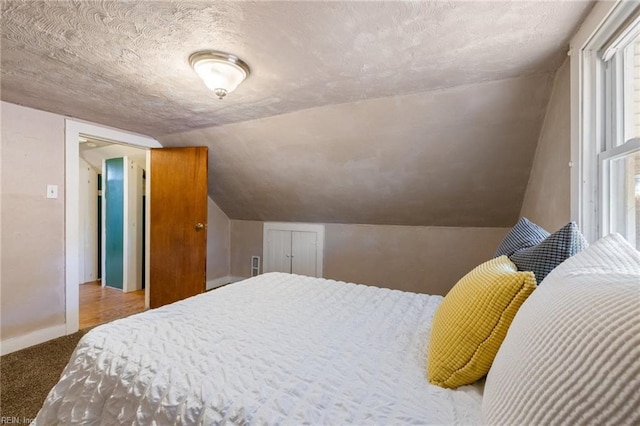 carpeted bedroom featuring baseboards, a textured ceiling, and lofted ceiling