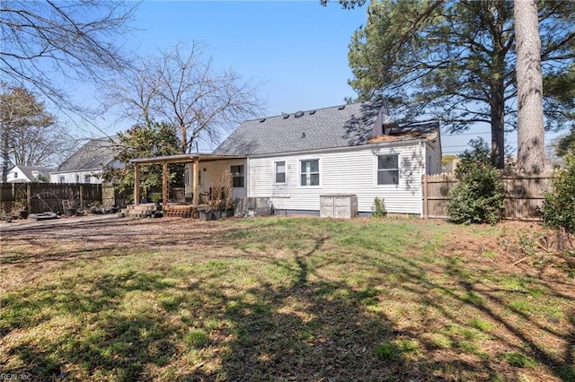 rear view of house featuring a deck, a lawn, a shingled roof, and a fenced backyard