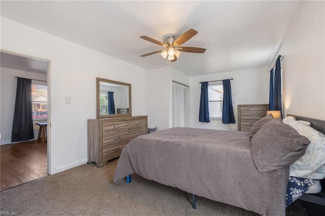 carpeted bedroom featuring baseboards, multiple windows, a closet, and a ceiling fan