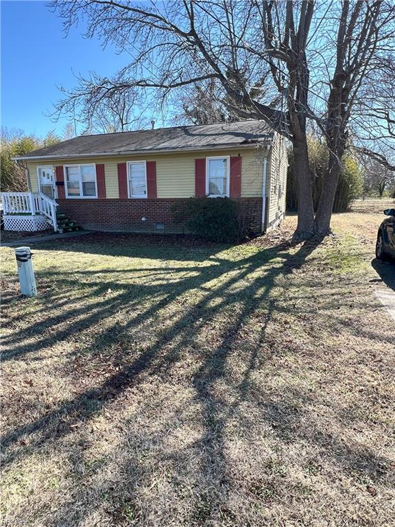 view of side of home featuring crawl space, brick siding, and a yard