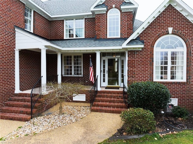 property entrance featuring crawl space, brick siding, a porch, and a shingled roof