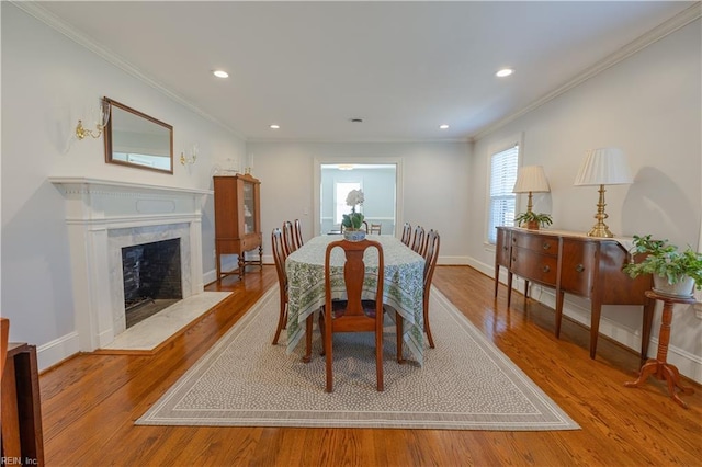 dining area with baseboards, ornamental molding, wood finished floors, and a high end fireplace