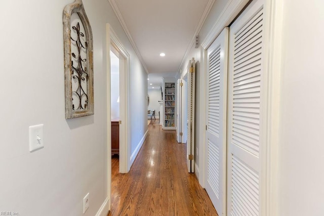 hallway with baseboards, ornamental molding, wood finished floors, and recessed lighting